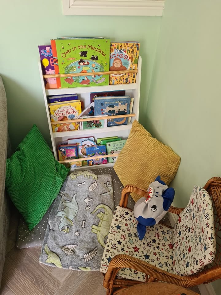A reading corner in the playroom with books, cushions and soft toys